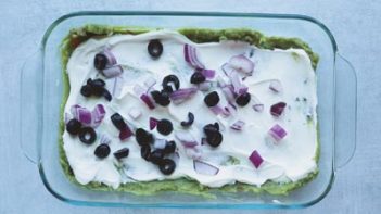 olives and onions spread over sour cream and guac