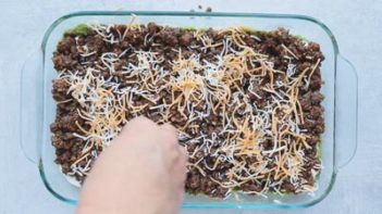 sprinkling shredded cheese on top taco meat