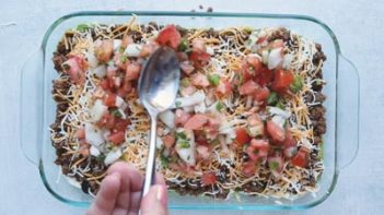 spooning pico de gallo on top a dip