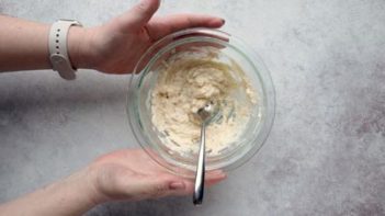 holding a bowl with mixed batter inside and a spoon