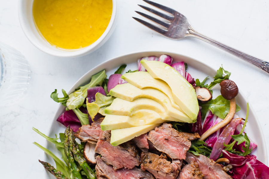 sliced avocado on top grilled steak salad