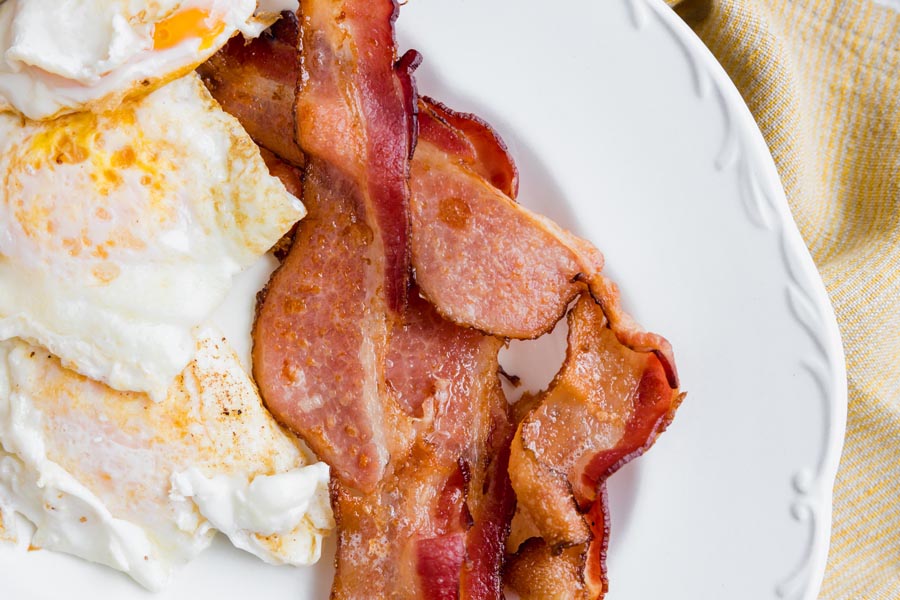 crispy bacon next to fried eggs