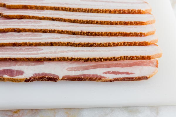 raw thick cut bacon layers on a cutting board
