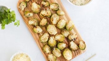 parmesan topped crispy brussels sprouts on a wooden board