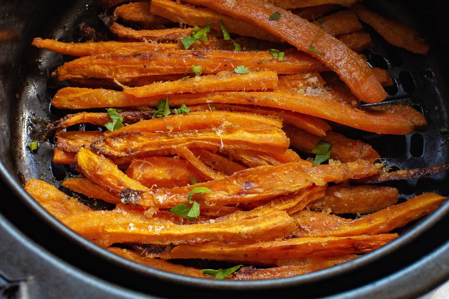 Crispy roasted carrot fries in an air fryer basket.