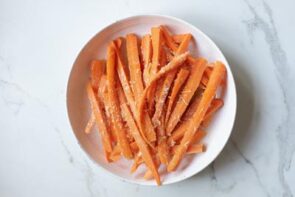 Raw carrot sticks topped with grated parmesan cheese.
