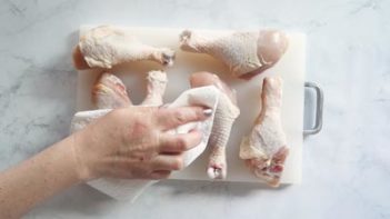 patting chicken dry with a paper towel