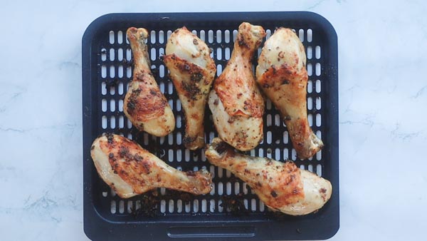 six chicken legs on an air fryer tray