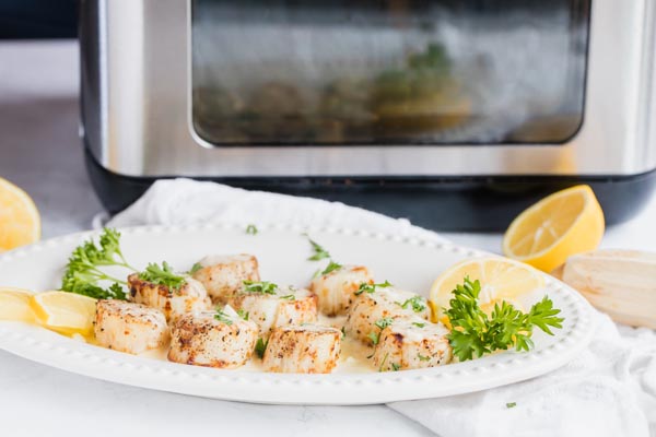 a plate of scallops sit in front of an air fryer