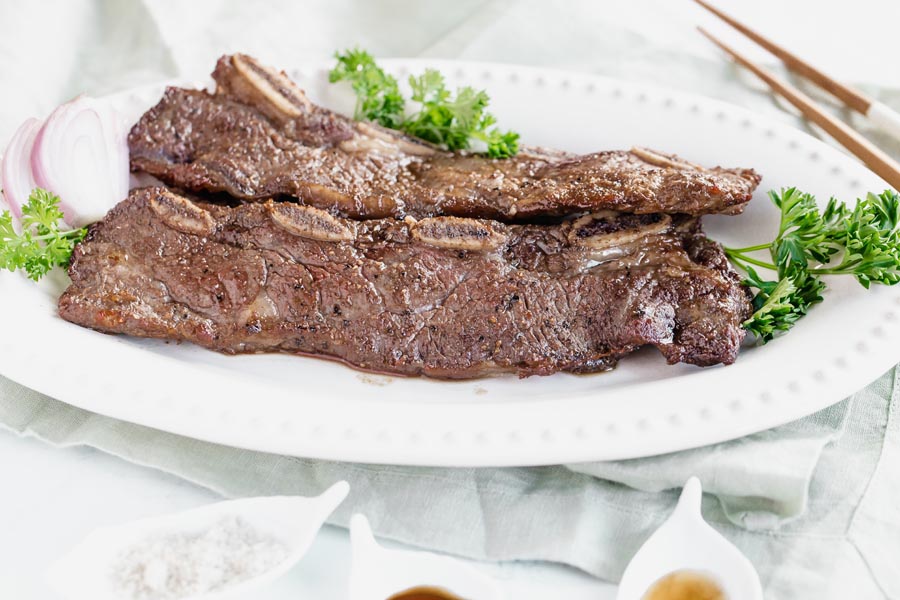 korean short ribs on a plate with chop sticks next to it