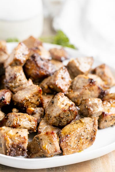 A plate of cut up pieces of cooked steak.