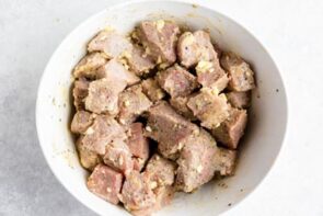 A bowl with steak pieces coated in butter and garlic.