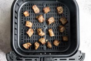 Cooked steak bites sitting in an air fryer basket.