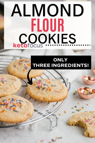 Almond flour cookies on a cooling rack with sprinkles scattered everywhere and a cookie with a bite out of it.