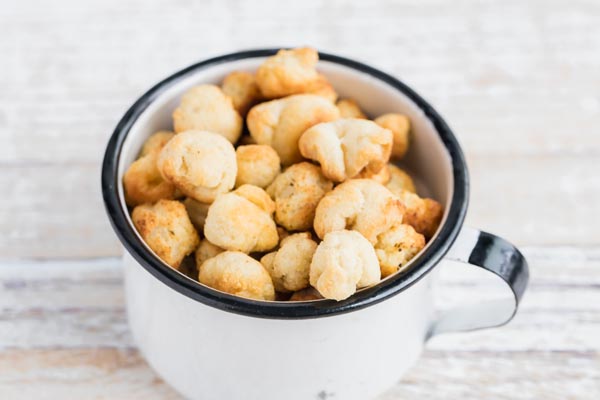 a white tin cup filled with crackers that look like popcorn