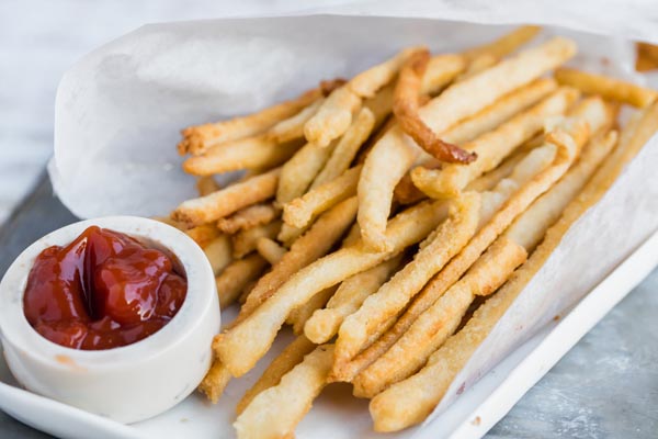 a bundle of keto fries wrapped in paper next to ketchup