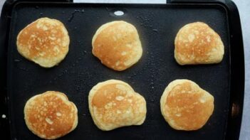 Golden brown pancakes on a griddle.