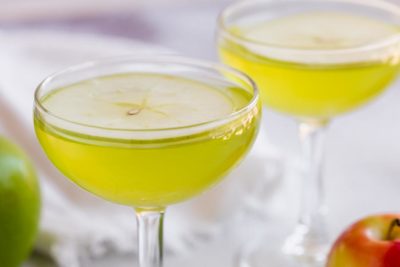 a crisp appletini in a martini glass topped with a green apple slice