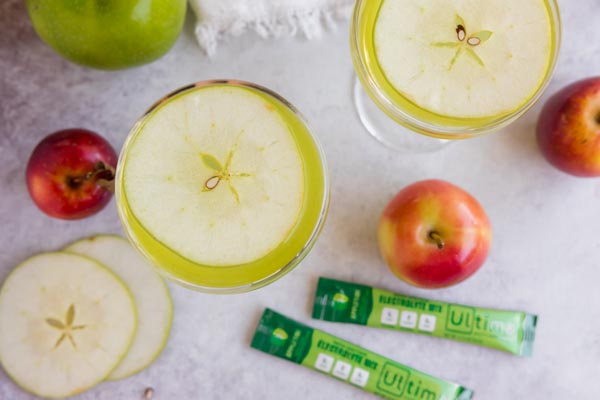 two apple cocktails with slices apples around and two packs of electrolytes