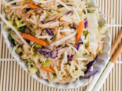 A bowl of Chinese chicken salad with canned chicken, cabbage, bean sprouts, carrots, green onions, and sesame dressing.