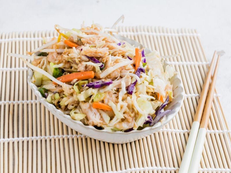 An easy Asian chicken salad served in a bowl with chopsticks on a bamboo placemat.