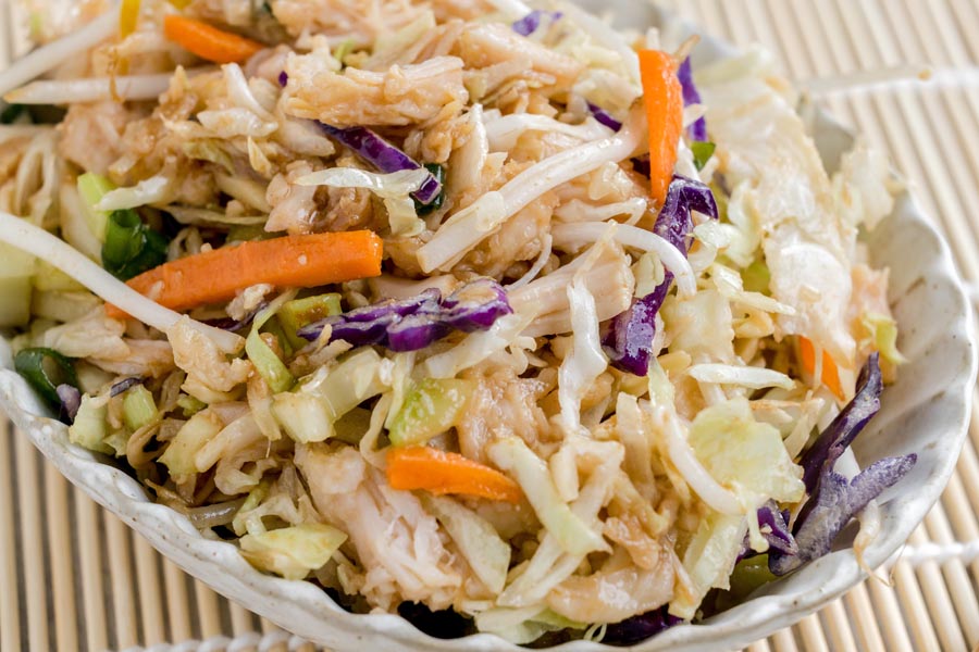 A close-up of Chinese chicken salad made with shredded chicken, cabbage, bean sprouts, carrots, and green onions.