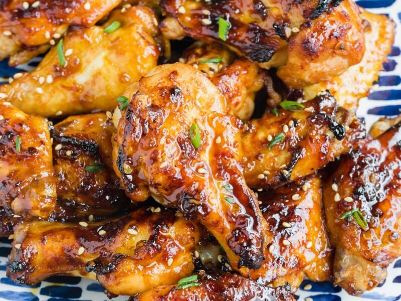 Sticky chicken wings coated in a spicy, sweet sauce and topped with sesame seeds and sliced green onions.