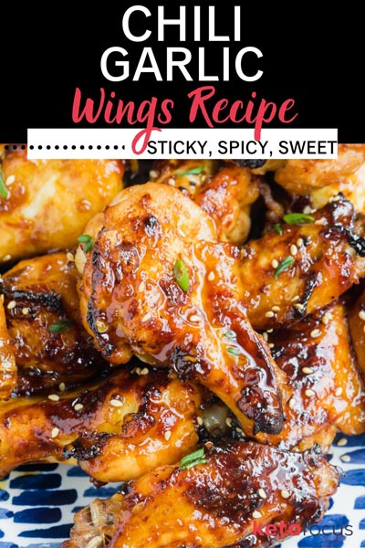 Sticky wings on piled on a plate coated in a golden sauce and topped with sliced green onions.