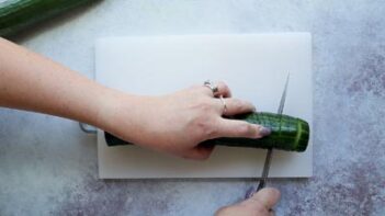 cutting a cucumber on a cutting board with a knife