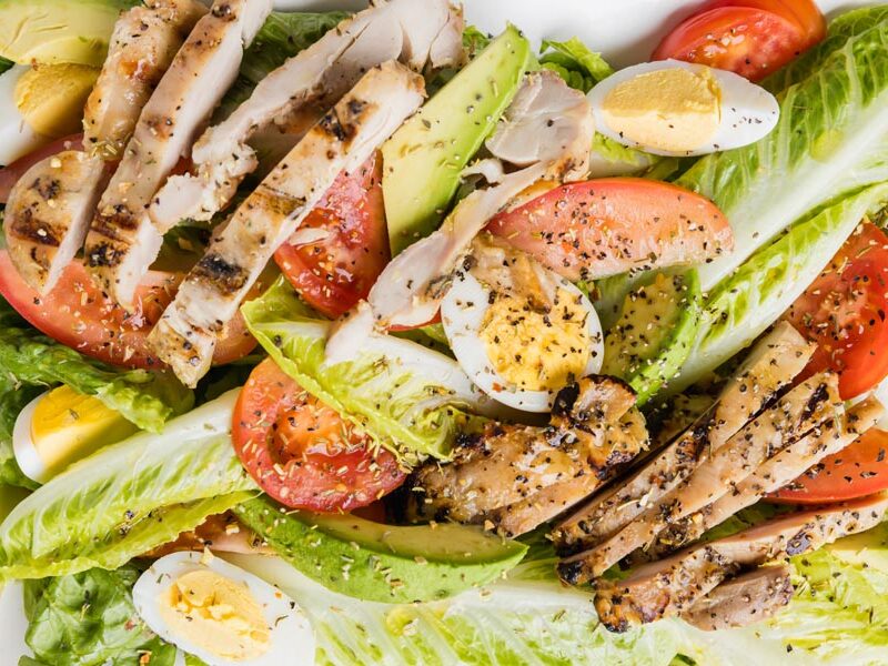 a grilled chicken salad with romaine lettuce, egg and tomato