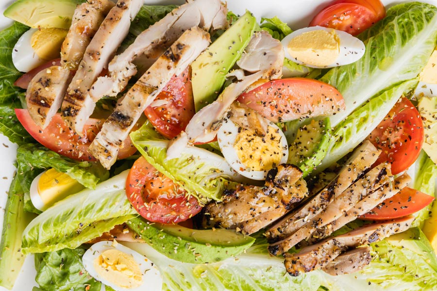 a grilled chicken salad with romaine lettuce, egg and tomato