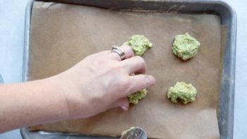 scooping green cracker mixture on a baking tray