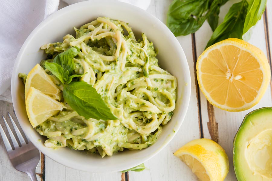 a bowl of pasta with lemon and avocado near
