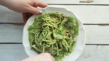 mixing avocado pesto sauce into chicken and noodles