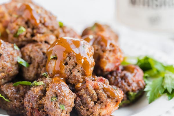 whiskey bbq sauce dripping of a plate of meatballs