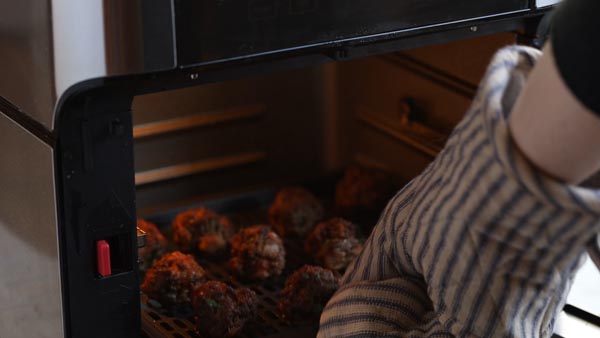 pulling cooked meatballs out of the air fryer