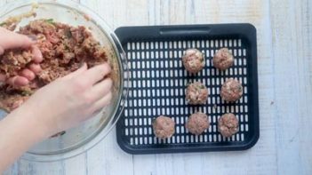 rolling meatballs and placing them on an air fryer tray