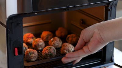 placing a tray of meatballs in the air fryer