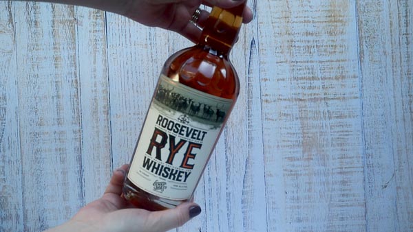 holding a bottle of rye whiskey