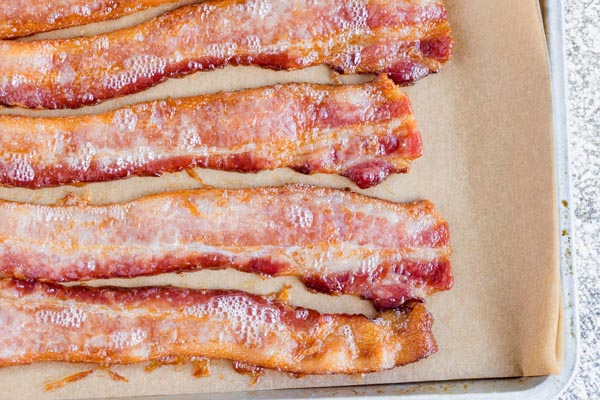 cooked bacon strips on a parchment lined cookie sheet