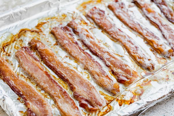 bacon sitting in bacon grease on a tray