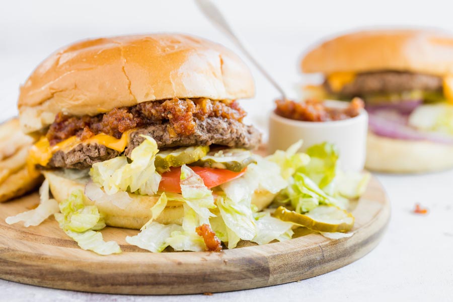 a burger with lettuce, tomato, pickle and bacon jam