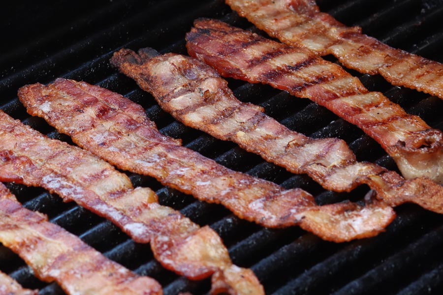 juicy crispy bacon cooking on a grill