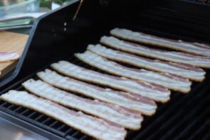 eight strips of raw bacon on a gas grill