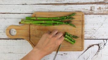 cutting asparagus stalks into smaller pieces with a knife