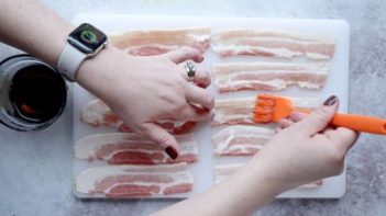 brushing maple syrup on a strip of bacon with a silicone basting brush