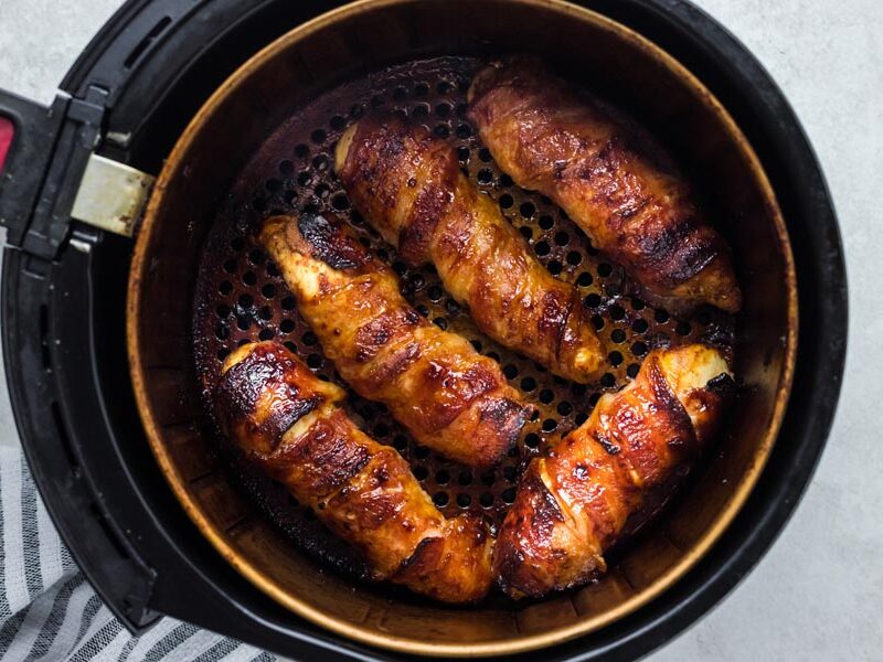Five bacon wrapped pieces of chicken baked in an air fryer.