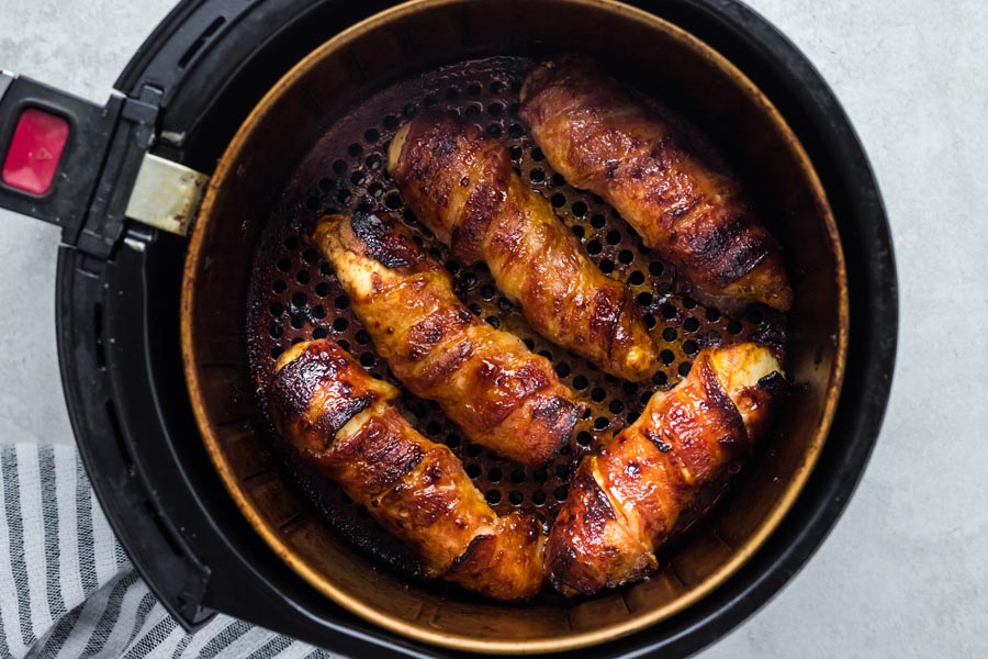 Five bacon wrapped pieces of chicken baked in an air fryer.