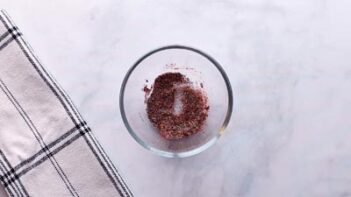 A glass bowl with smoked paprika seasoning mixed inside.