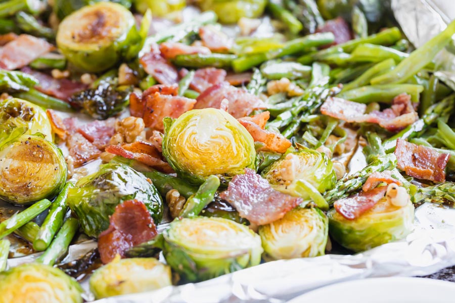 roasted vegetables and bacon on a sheet pan